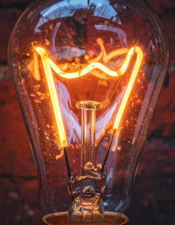 A classic Edison bulb flickers to life, its intricate filament casting a warm, inviting glow.の素材