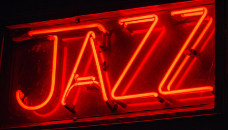 A vibrant red neon sign glows in the darkness, spelling out the word 'JAZZ'.の素材