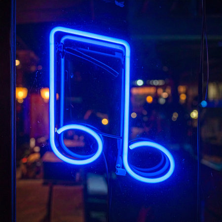 A vibrant blue neon sign, shaped like a musical note, glows brightly in a window against the dark backdrop of the city at night.の素材