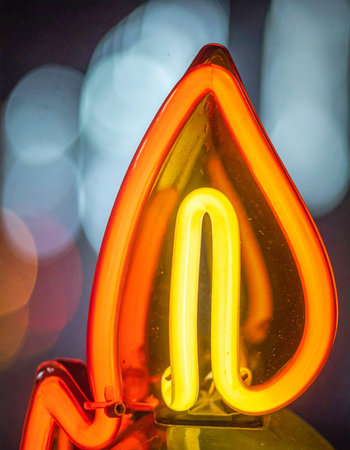 A vibrant neon flame glows with intense orange and yellow light, casting a warm and inviting ambiance.の素材