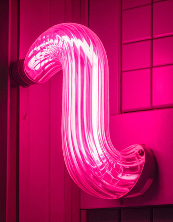 A futuristic pink neon sculpture casts a vibrant, electric glow, illuminating a dark, modern space.の素材