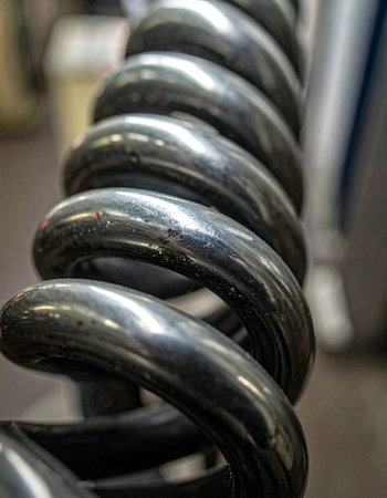 A detailed macro shot captures the immense potential energy stored within the coils of a heavy-duty industrial spring.の素材