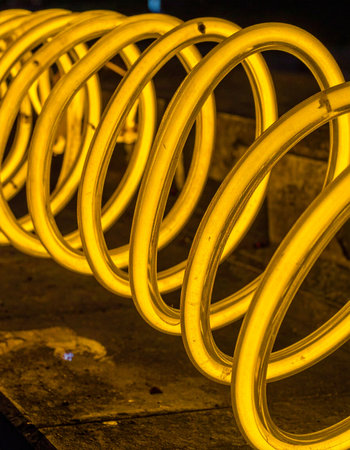 A vibrant yellow coil glows with intense energy, its spiral form creating a mesmerizing pattern of light and shadow.の素材
