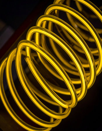 A vibrant spiral of yellow light coils with intense energy against a deep black void.の素材