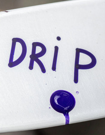A conceptual macro photograph shows the word 'drip' handwritten in vibrant purple ink.の素材