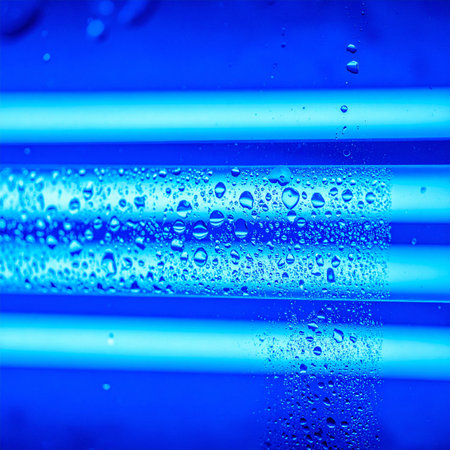 Intense blue ultraviolet light radiates from parallel tubes, a core component in a modern water purification system.の素材
