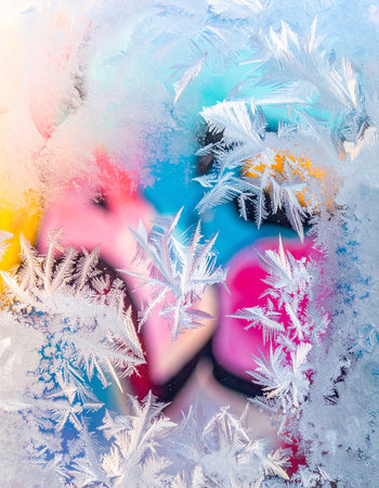 Intricate ice crystals form a delicate lace pattern on a frozen window pane.の素材