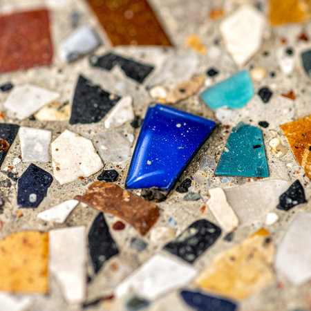 A striking macro view of a modern terrazzo surface, where a polished, vibrant blue stone stands out as a focal point among a mosaic of colorful, recycled glass and marble chips.の素材