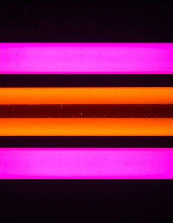 Parallel beams of vibrant pink and orange neon light cut through the darkness, creating a futuristic and energetic atmosphere.の素材