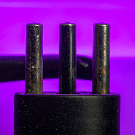 A detailed macro shot captures the weathered texture of a vintage three-pronged electrical plug, set against a vibrant, glowing purple background.の素材