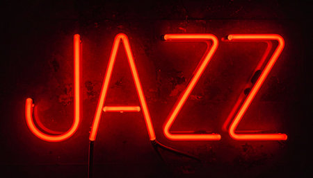 The vibrant red glow of a classic neon sign cuts through the darkness, spelling out the word 'JAZZ'.の素材