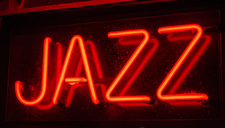 The vibrant red glow of a neon sign cuts through the darkness, spelling out the word 'JAZZ'.の素材