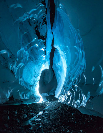 Deep within a vast glacier, a hidden chamber glows with an otherworldly blue light.の素材