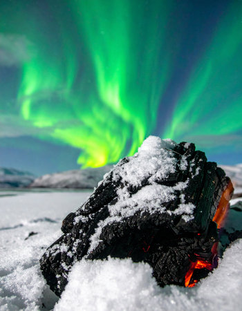 A stunning display of nature's raw power, where the celestial dance of the green aurora borealis illuminates a frozen landscape.の素材