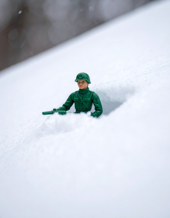 A miniature green toy soldier perseveres through a deep, unforgiving snowdrift.の素材