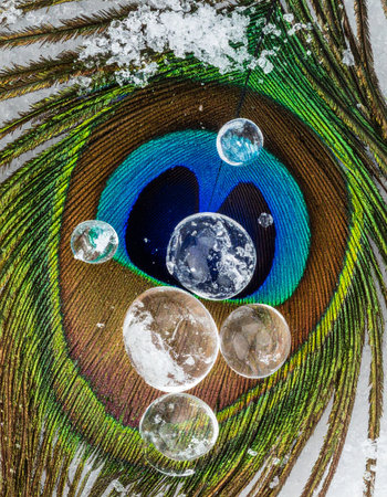 A surreal macro view captures tiny liquid worlds, like distant planets or galaxies, resting upon the iridescent and intricate patterns of a peacock feather.の素材