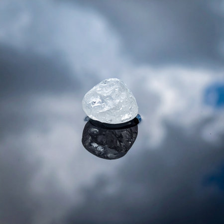 A single, uncut rough diamond rests on a mirrored surface, its raw potential captured in a moment of serene reflection.の素材