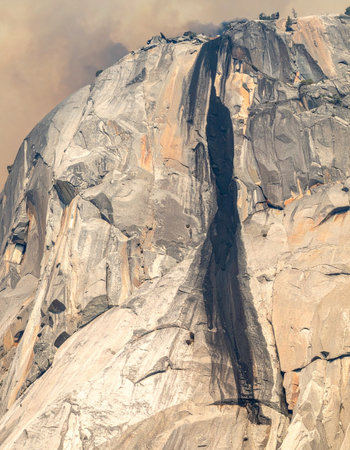 Carved by time and water, a mysterious female figure emerges from the sheer granite face of a mountain.の素材