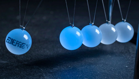 A single luminous sphere labeled 'ENERGY' swings towards a line of others in a Newton's cradle, poised to initiate a chain reaction.の素材