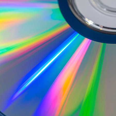 A macro view captures the mesmerizing play of light on a compact disc's surface.の素材