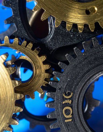 A macro view captures the intricate dance of interlocking brass and steel gears.の素材