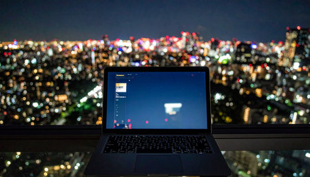 From a high-rise vantage point, a lone computer screen glows, a beacon of productivity against the sprawling, out-of-focus city lights.の素材