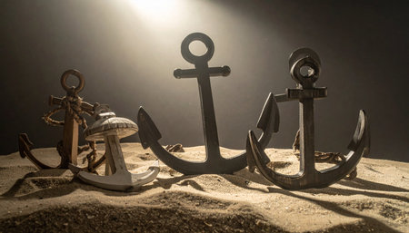 Bathed in a single ray of light, three vintage anchors rest on the sandy floor, silent storytellers of countless voyages.の素材