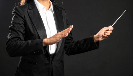 With a precise flick of the baton and a graceful gesture, a conductor in a sharp suit orchestrates a symphony of sound.の素材