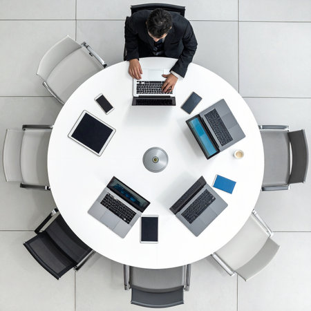 An executive sits alone at a large, modern conference table, seen from a top-down perspective.の素材