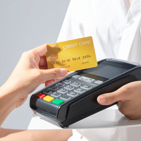 A customer completes a quick and secure purchase by simply tapping their gold credit card on the payment terminal.の素材