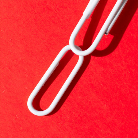 A single white chain link stands out against a bold red background, creating a powerful visual metaphor.の素材