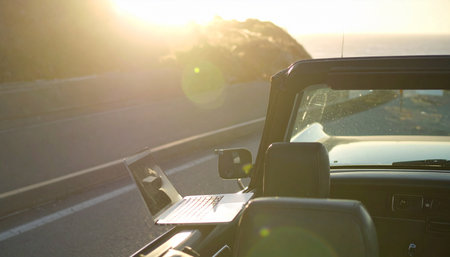 Cruising down a scenic highway in a classic convertible as the warm, golden sun sets on the horizon.の素材