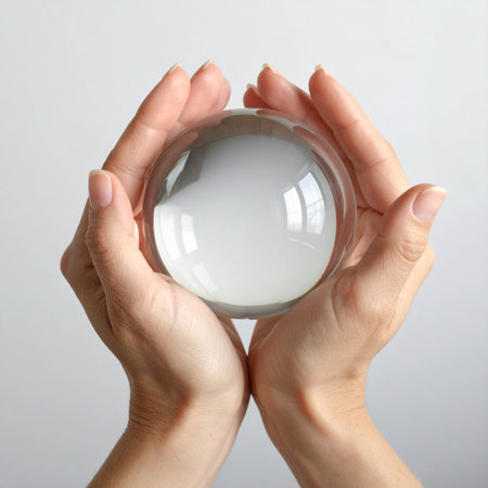 A pair of gentle hands carefully holds a clear crystal ball, representing a glimpse into the future.の素材