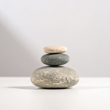 A simple stack of three smooth stones stands in perfect equilibrium against a clean, bright background.の素材