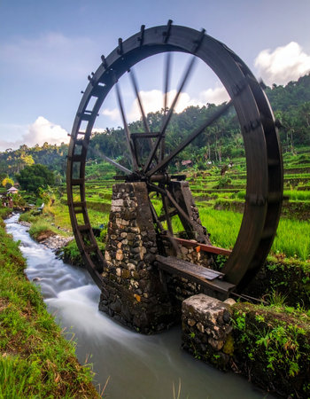 An ancient wooden water wheel turns with the steady flow of a stream, its perpetual motion a testament to timeless engineering.の素材