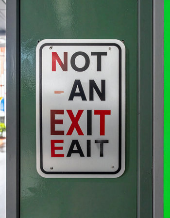 A clear and direct 'Not An Exit' sign mounted on a green surface provides an unmistakable warning.の素材