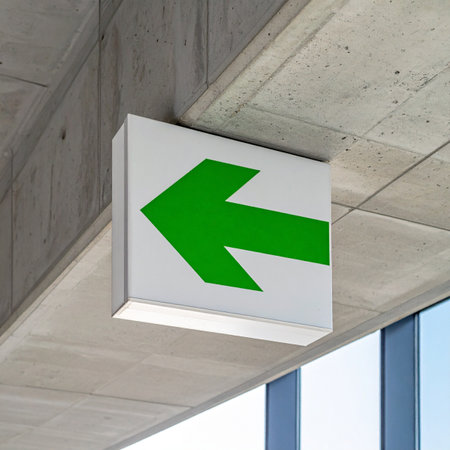 A clear, green arrow sign provides unambiguous direction, mounted on a raw concrete ceiling in a modern architectural setting.の素材