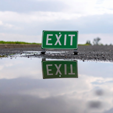 An exit sign stands on a wet road, its clear reflection mirrored in a still puddle after a rain.の素材