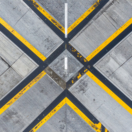 From a top-down perspective, the weathered surface of an airport tarmac reveals a striking geometric pattern.の素材