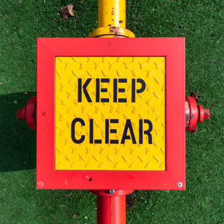 A bold 'KEEP CLEAR' sign stands as a constant, silent guardian on a fire hydrant.の素材
