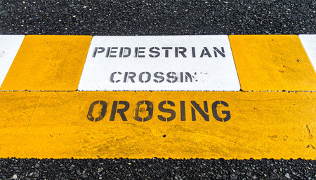 A detailed view of a stenciled pedestrian crossing sign on the textured asphalt.の素材