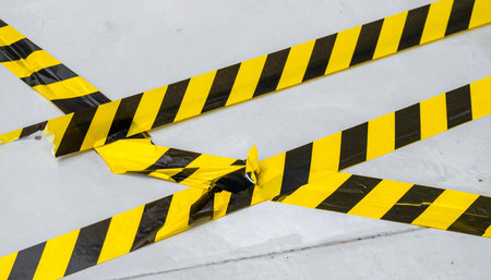In the chaotic aftermath of an incident, tangled yellow and black hazard tape lies strewn across the floor.の素材