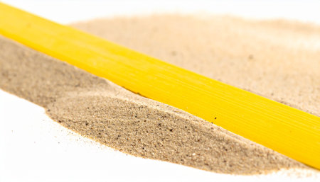 A vibrant yellow line cuts a path through a mound of fine, textured sand.の素材