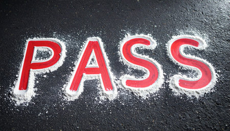 The word 'PASS' is written in bold red letters on a dark, textured surface, highlighted by a sprinkle of white powder.の素材