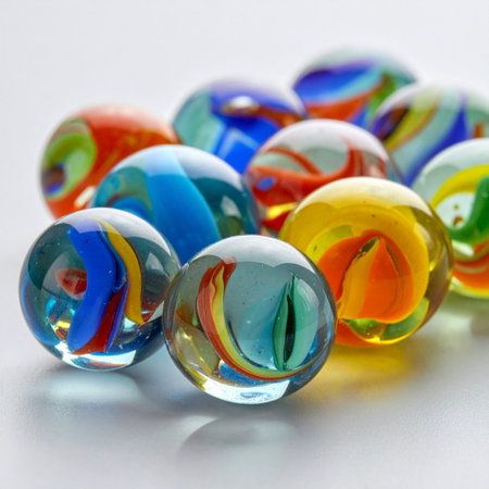 A close-up shot captures the vibrant swirls and glossy reflections of a collection of classic glass marbles.の素材