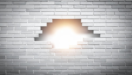 A brilliant burst of warm light breaks through a solid brick wall, creating a powerful visual metaphor for overcoming obstacles.の素材