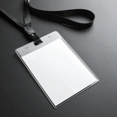 A clean and professional blank ID badge with a black lanyard rests on a dark surface, ready for custom branding.の素材