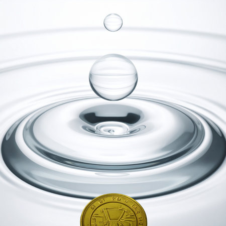 A crystal clear water drop hovers in perfect suspension, creating a ripple effect on the surface below.の素材