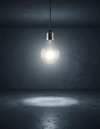 In the quiet emptiness of a stark concrete room, a single lightbulb hangs, casting a bright, focused glow.の素材
