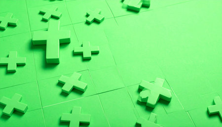 Vibrant green puzzle pieces are scattered across a matching background, with some beginning to connect.の素材